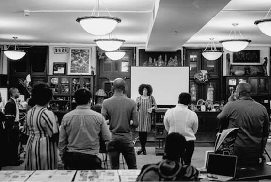 People standing in a room together with light fixtures hanging from the ceiling.