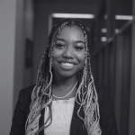 A person with long braided hair in a hallway.