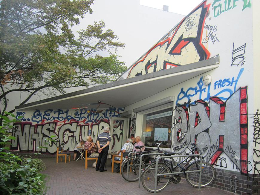 graffiti at an outdoor cafe with men sitting at a table