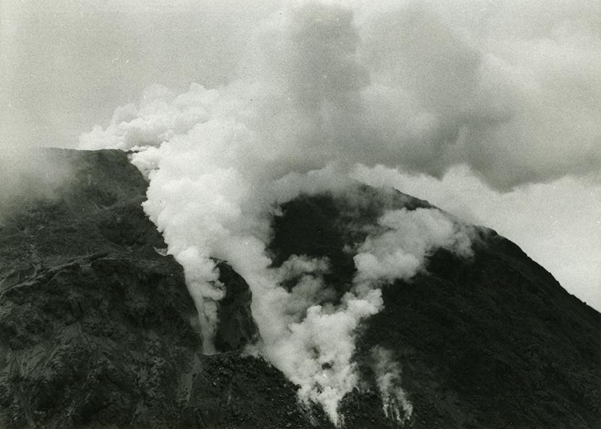 black and white photo of a mountain with fires and smoke burning on it